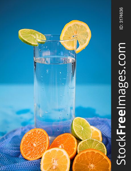 Oranges and lemons in transparent glass over blue background