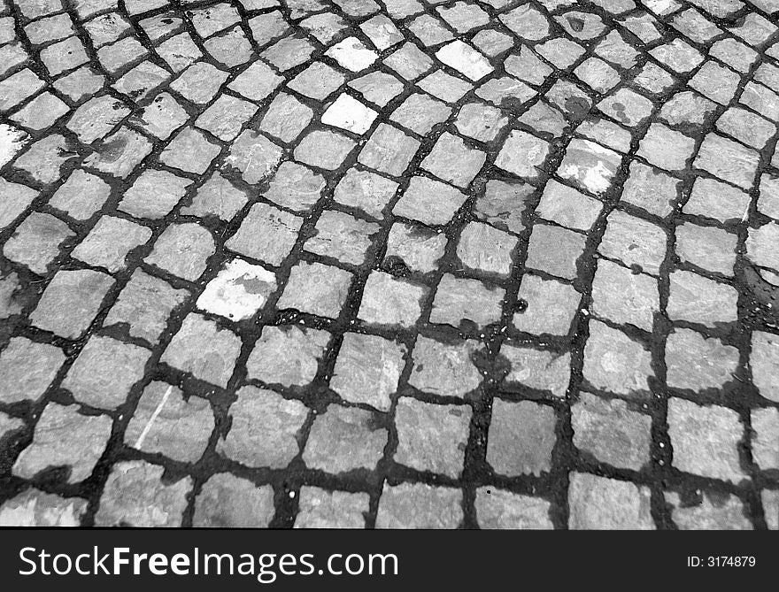 Background of cobblestone pavement to convey the idea of unevenness, circular pattern, with tufts of grass and dirt sticking out. Background of cobblestone pavement to convey the idea of unevenness, circular pattern, with tufts of grass and dirt sticking out.