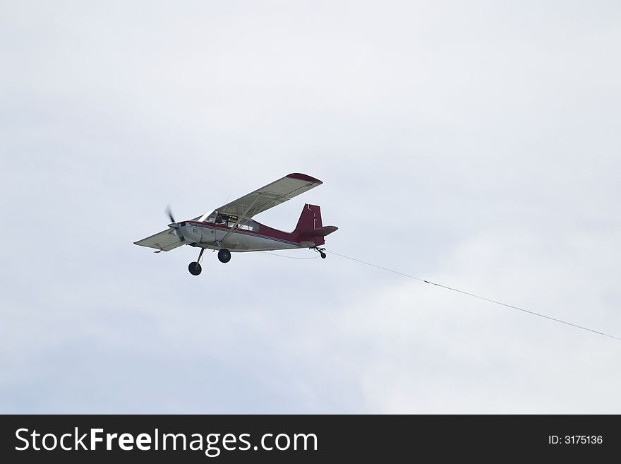 Airplane flying in the sky with a tow cable. Airplane flying in the sky with a tow cable.