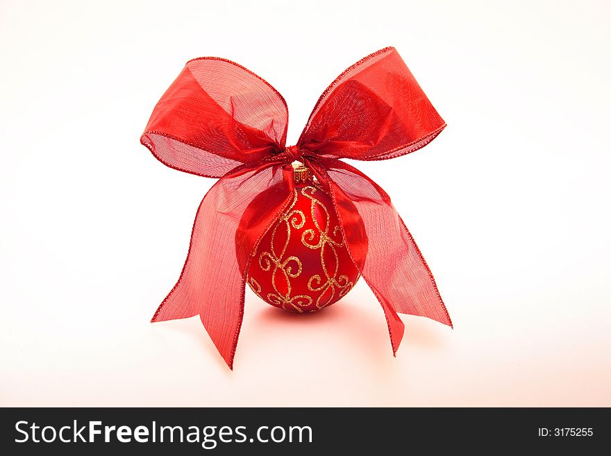 An isolated red Christmas ball tied with a red ribbon against a white background. An isolated red Christmas ball tied with a red ribbon against a white background.