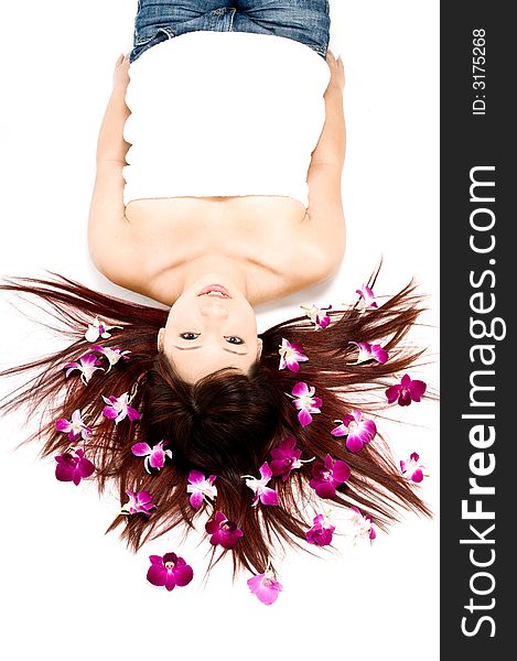 A young Asian woman lying on the floor with purple orchid flowers. A young Asian woman lying on the floor with purple orchid flowers