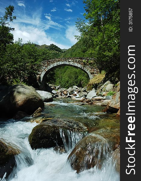 Aged arch bridge over a small mountain river