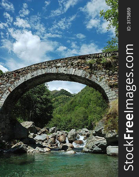 Aged arch bridge over a small mountain river