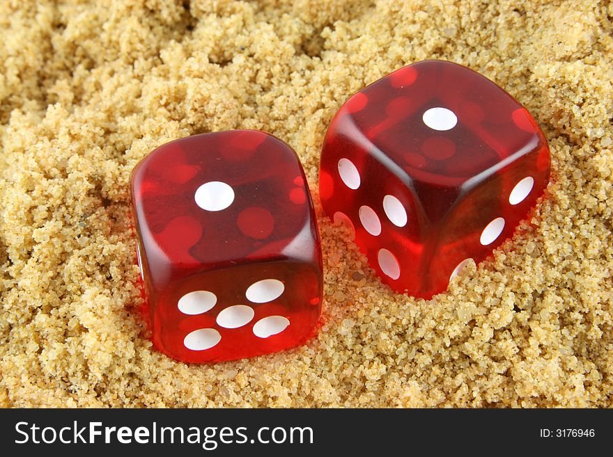 2 Dice showing snake eyes - half buried in the sand