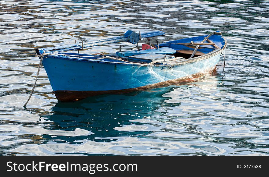 Small blue boat rests at anchor. Small blue boat rests at anchor