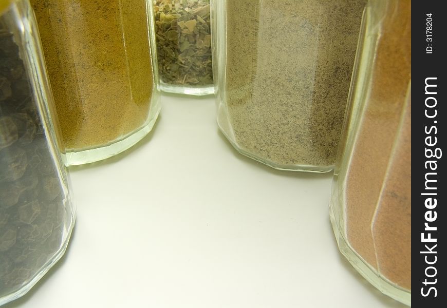 Ground spices in glass tableware and whole black pepper