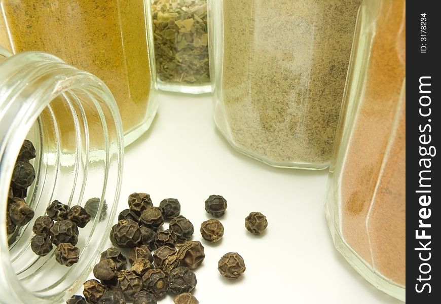 Ground spices in glass tableware and whole black pepper