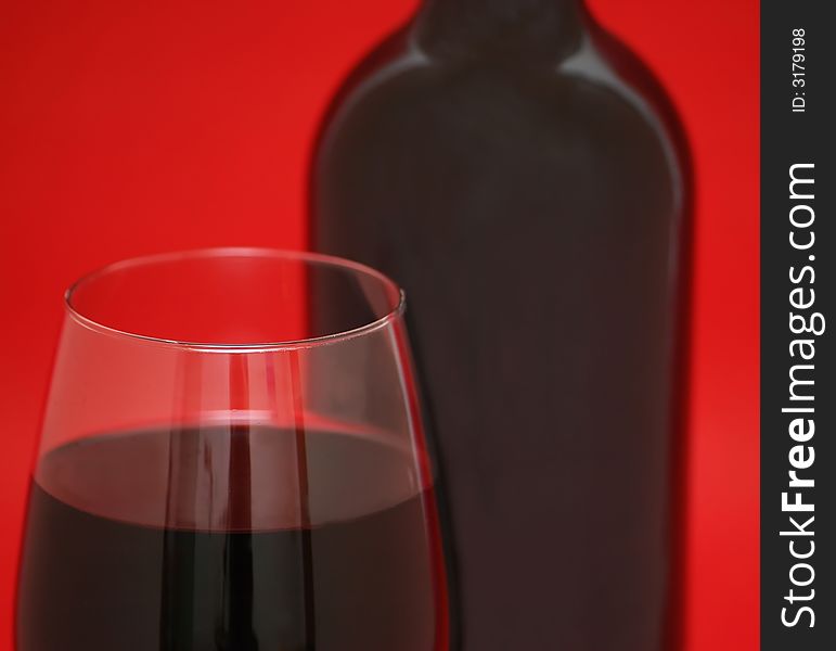 Glass and bottle of wine on the red background