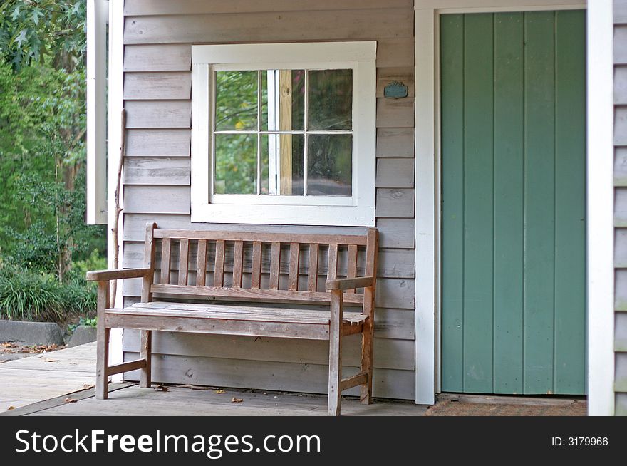 An old wooden bench on the porch of a small cabin. An old wooden bench on the porch of a small cabin