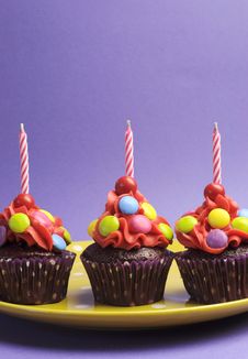 Three Bright Candy Covered Cupcakes With Birthday Candles - Vertical Stock Photo Three Bright Candy Covered Cupcakes With Birthday Candles - Vertical Stock Photo