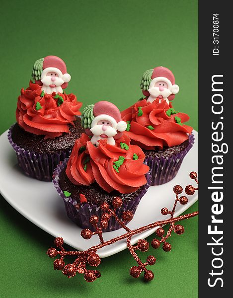 Three Christmas Cupcakes against a green background - vertical