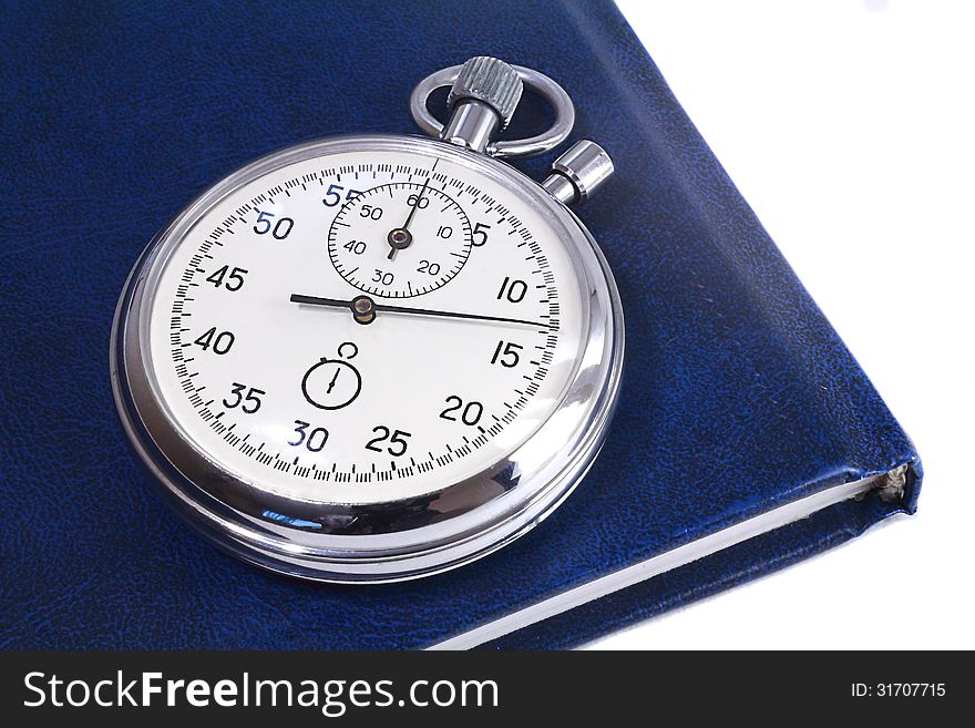 Shiny metal stopwatch and notebook blue. Presented on a white background. Shiny metal stopwatch and notebook blue. Presented on a white background.