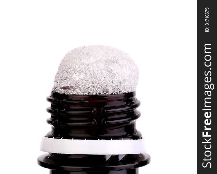 Froth cap of open beer bottle close-up on the white background