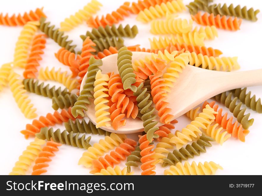 A pasta eliche tricolori and a wood spoon.