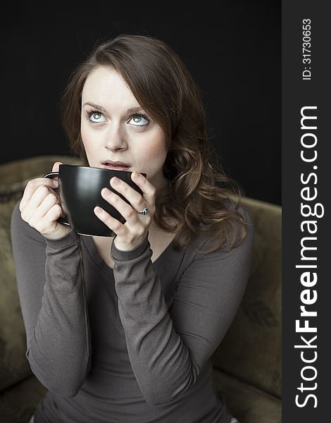 Portrait of a beautiful young woman with beautiful green eyes and brown hair holding a black coffee cup. Portrait of a beautiful young woman with beautiful green eyes and brown hair holding a black coffee cup.