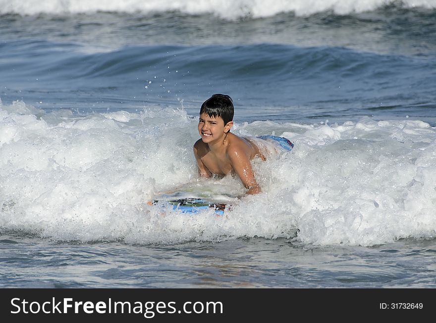 A boy with his tablet to surf on blue waves of the Mediterranean Sea. A boy with his tablet to surf on blue waves of the Mediterranean Sea