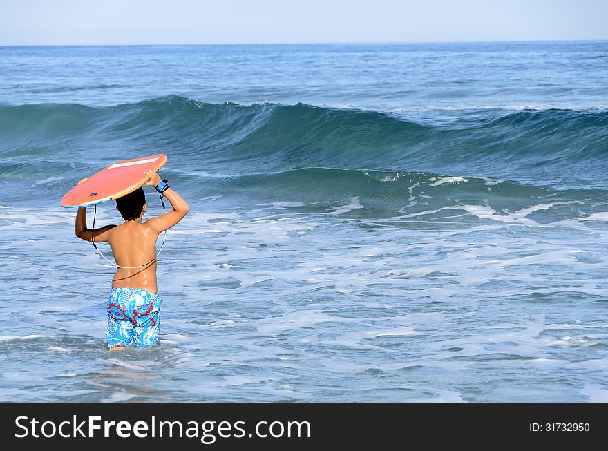 A boy with his tablet to surf on blue waves of the Mediterranean Sea. A boy with his tablet to surf on blue waves of the Mediterranean Sea