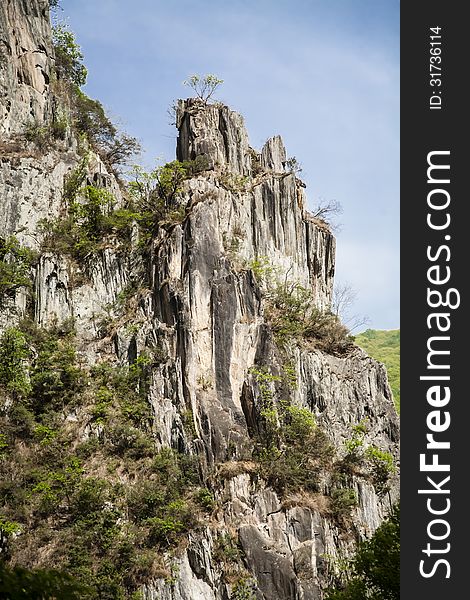 Many trees grow along the edges of this classic looking, rough Chinese mountainside, but only a few lonely ones make it to the top to contrast against the scattered clouded blue sky. Many trees grow along the edges of this classic looking, rough Chinese mountainside, but only a few lonely ones make it to the top to contrast against the scattered clouded blue sky.