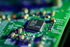 Green Circuit Board With A Black Integrated Circuit Chip And Various Small Electronic Components Stock Photo