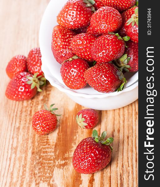 Dish of ripe strawberries on a wooden table. Dish of ripe strawberries on a wooden table