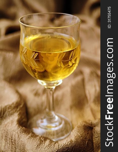 White wine in crystal glass and golden backcloth