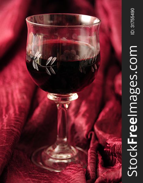 Red wine in crystal glass and red backcloth