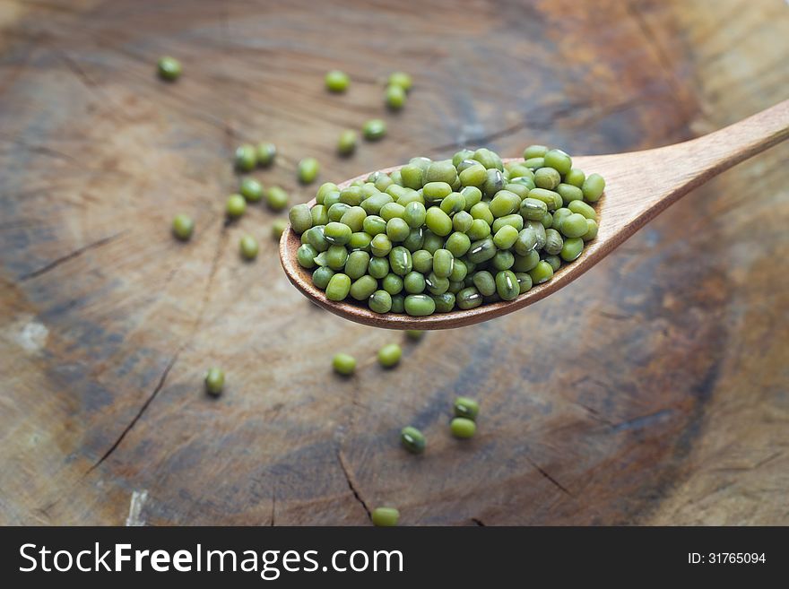 Mung beans over wooden spoon on wood background