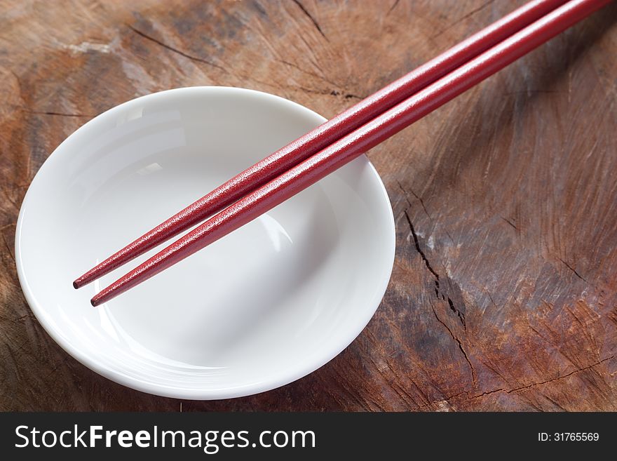 Two chopsticks next to a red and white bowl
