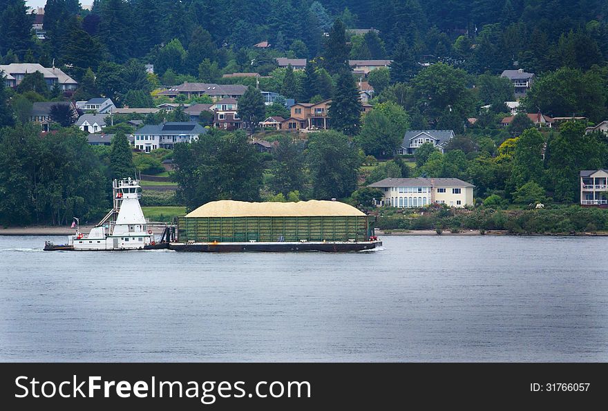 A tugboat pushing a heavy barge in the traffic lane in the Columbia River Gorge. Common daily scene. A tugboat pushing a heavy barge in the traffic lane in the Columbia River Gorge. Common daily scene.