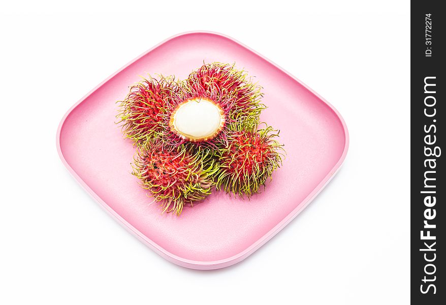 Rambutan in pink dish isolated on white background.