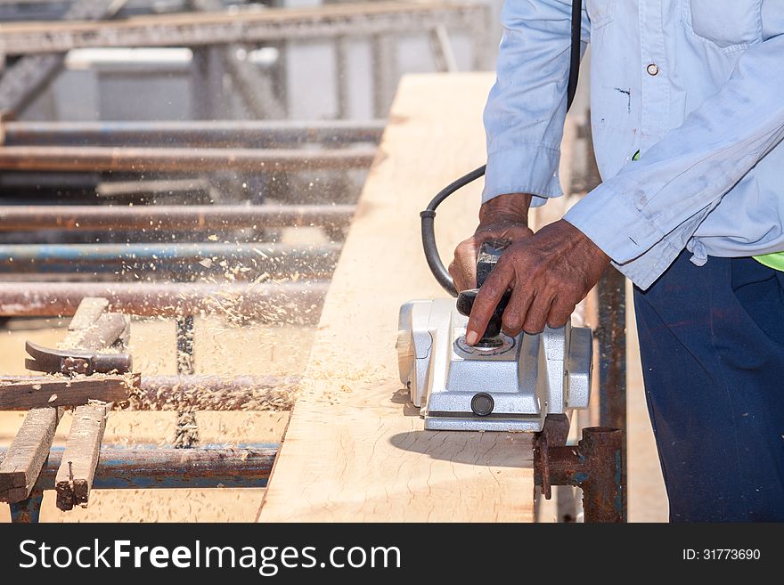 The carpenter planing log by using electric planer. The carpenter planing log by using electric planer