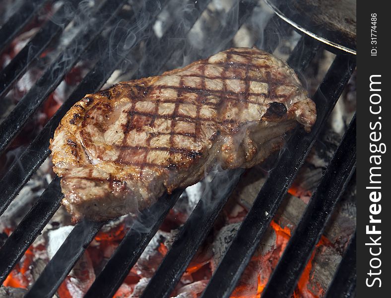 Beef steak cooking on an open flame grill