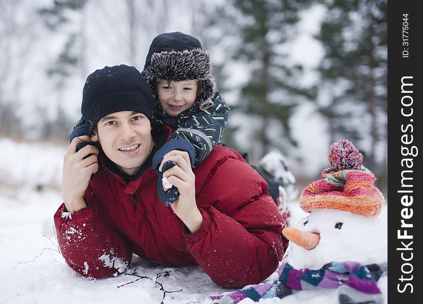 Portrait of happy father with his son outside with snowman
