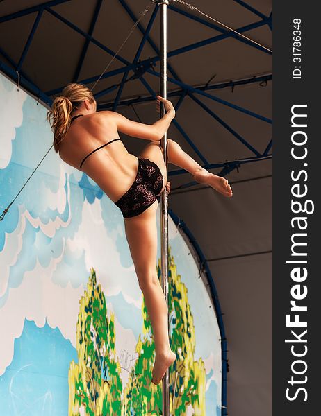 Young gymnast girl doing exercises in the sport pole