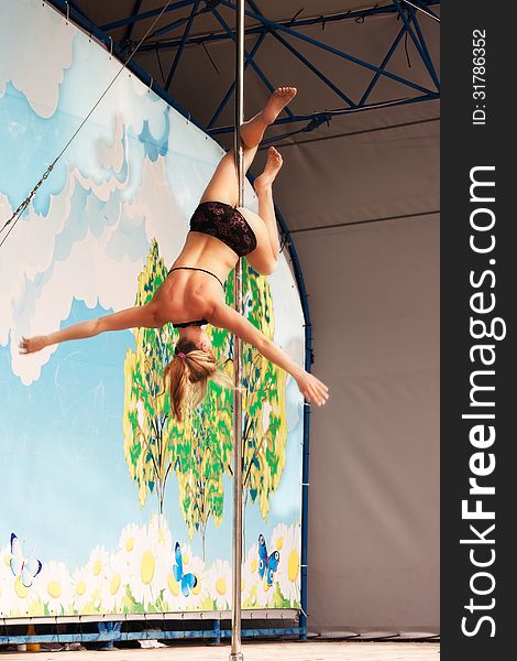 Young gymnast girl doing exercises in the sport pole