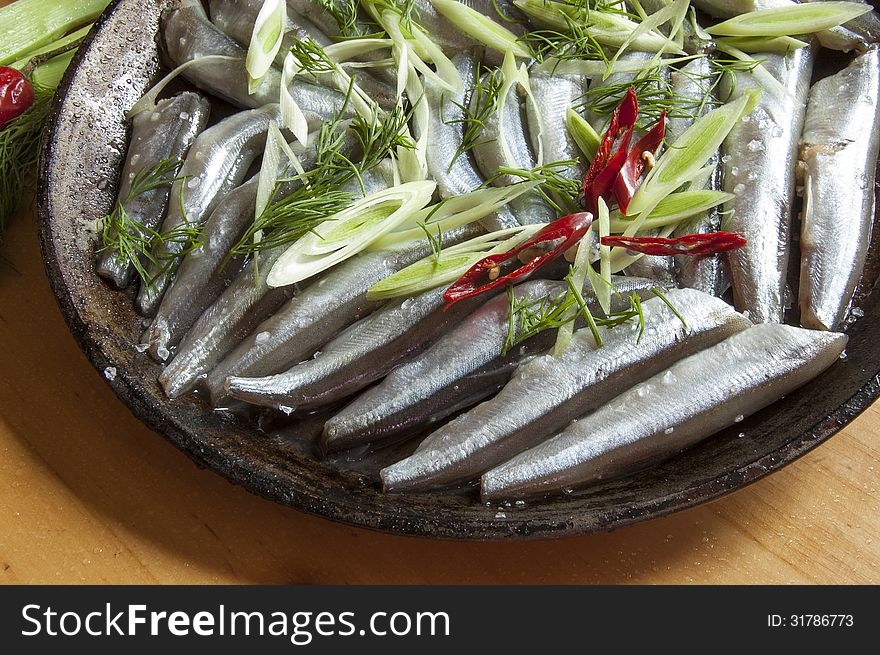 The process of cooking fish. Fresh fish on an old frying pan. Horizontal image, macro. The process of cooking fish. Fresh fish on an old frying pan. Horizontal image, macro.