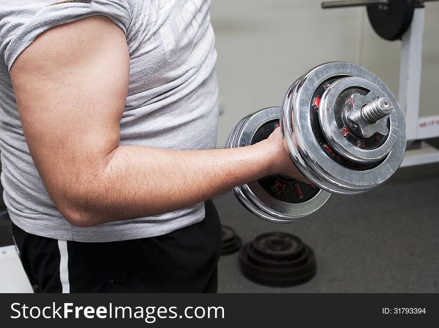 The guy lifts a dumbbell, is photographed by a close up