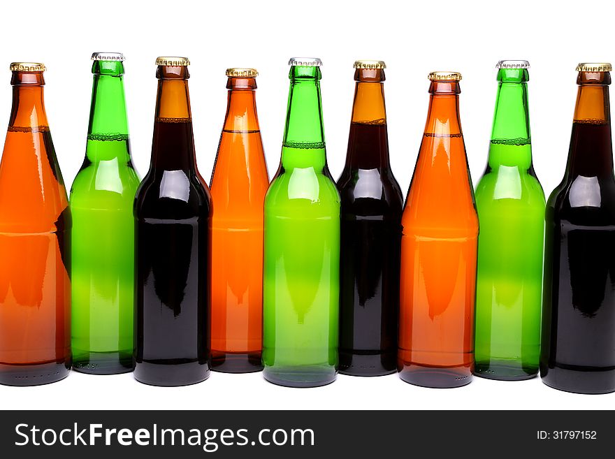 A row of six beer bottles on a white background with a reflection. A row of six beer bottles on a white background with a reflection.