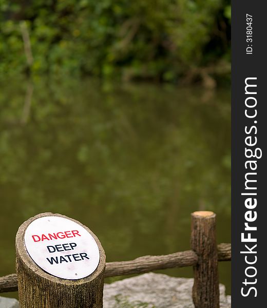 Elliptical aluminum plate etched with the words Danger, in red, and Deep Water, in black, besides a disused quarry, that is flooded. Elliptical aluminum plate etched with the words Danger, in red, and Deep Water, in black, besides a disused quarry, that is flooded.