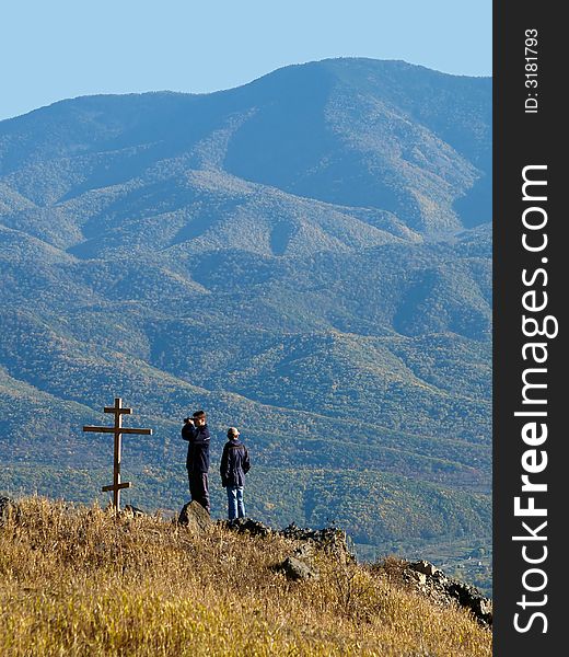 Fall panorama landscape with two hikers standing on the mountain top near the christian rood. Fall panorama landscape with two hikers standing on the mountain top near the christian rood