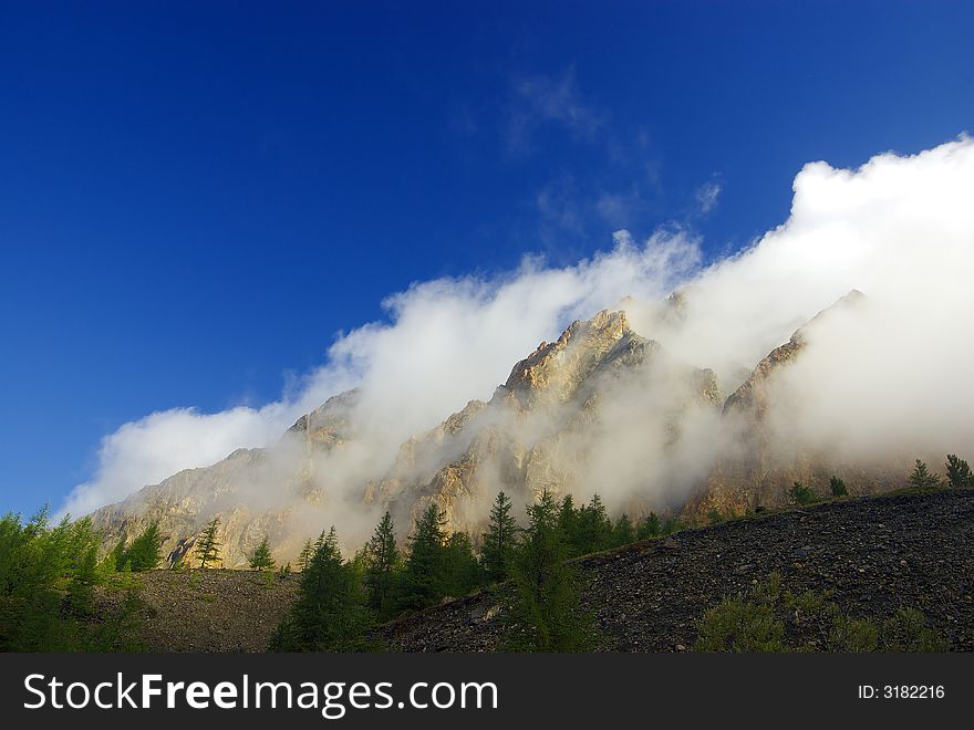 Morning wind blows clouds over rock. Morning wind blows clouds over rock