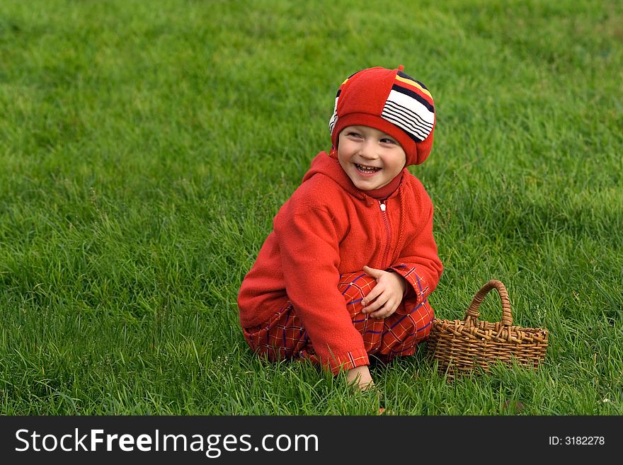 Child sits on a green grass with a basket. Child sits on a green grass with a basket