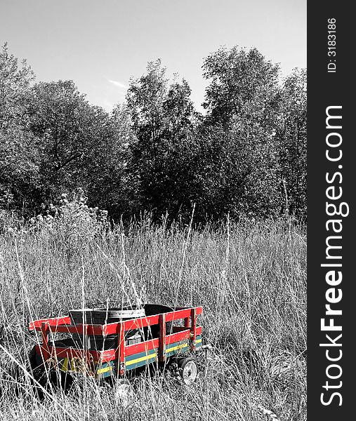 A little red wagon is abandoned in a black and white field. A little red wagon is abandoned in a black and white field.