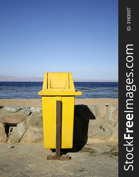 Yellow dustbin on wallway by seaside