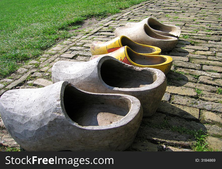 Real original and traditional wooden shoes (some with woodworm) on a brick road. Real original and traditional wooden shoes (some with woodworm) on a brick road