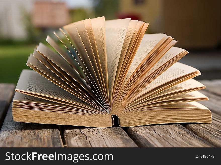 The book is laying on a old wooden table. The book is laying on a old wooden table