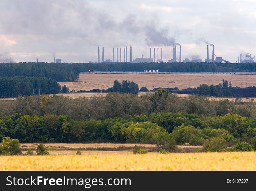 Factory chimneys under autumn fields