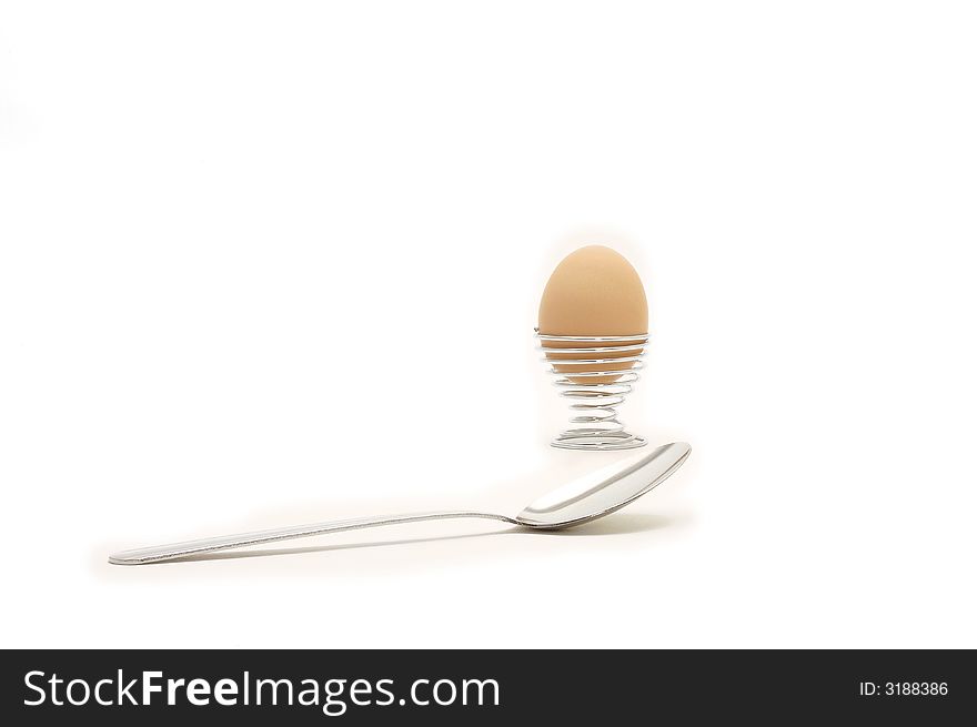 An image of a egg in a holder with spoon over white. An image of a egg in a holder with spoon over white