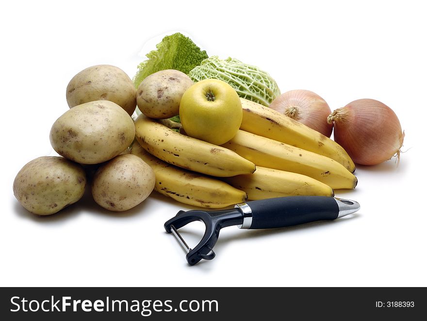 An image of various fruit and vegatables with peeler over white