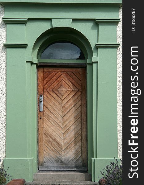 An old wooden door with green painted decorative stone surround. An old wooden door with green painted decorative stone surround